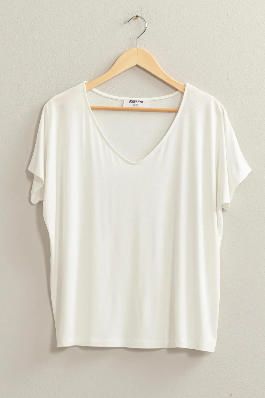 full length front view of the andi tee in the color ivory,handing on a wooded hangar 