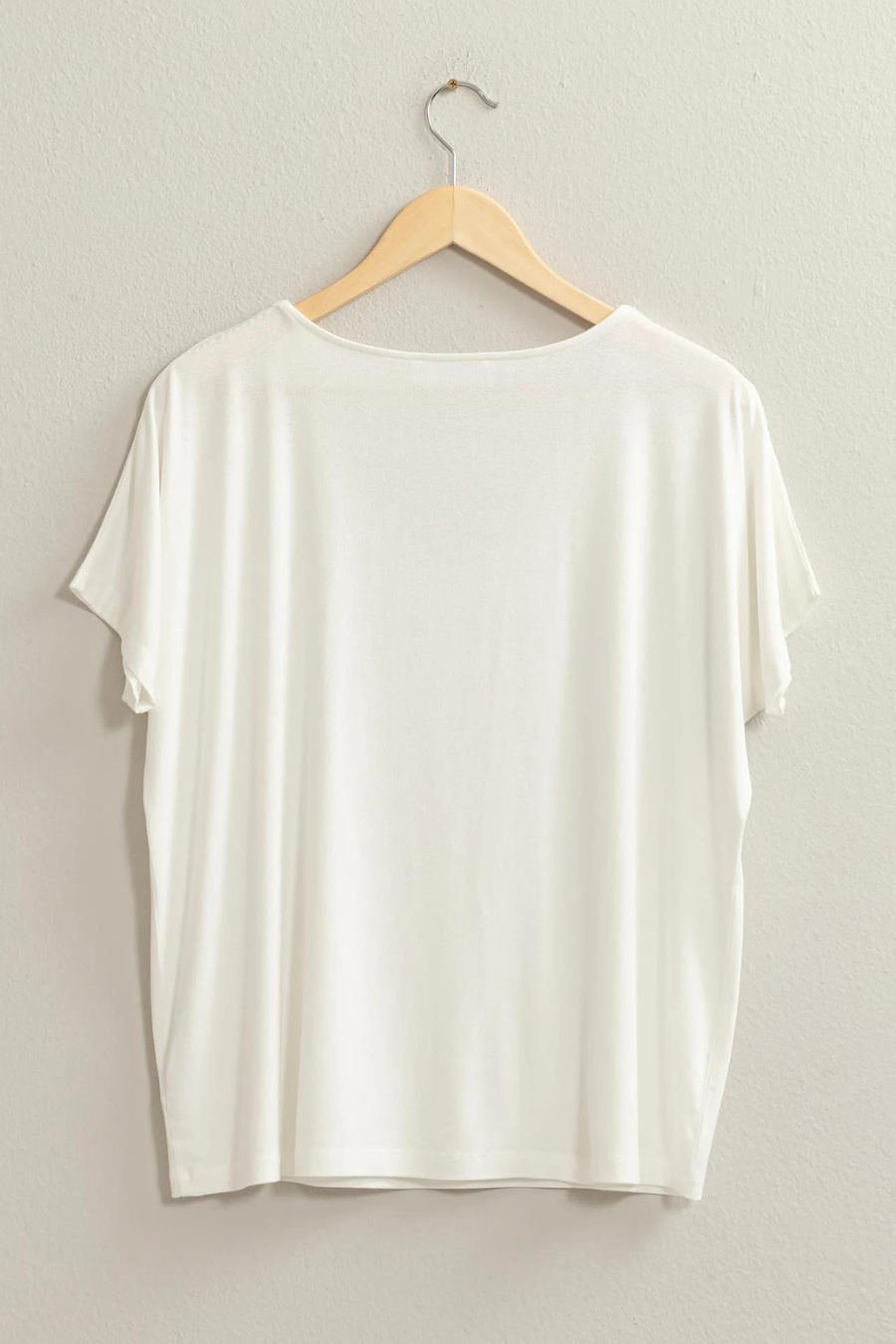 full length back view of the andi tee in the color ivory, hanging on a wooden hanger 