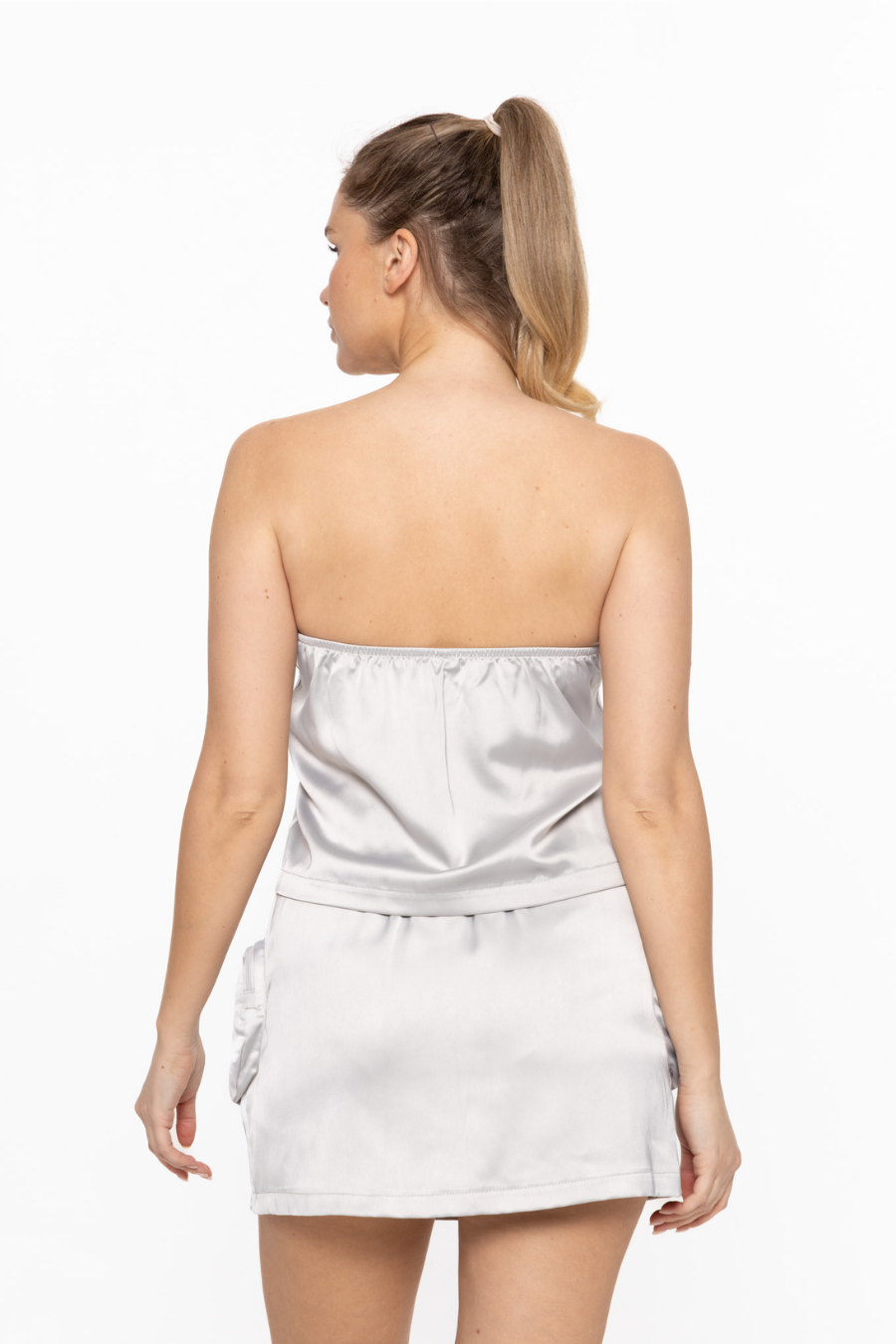 back view of smooth stride loose tube top in silver. model is wearing it with matching skort
