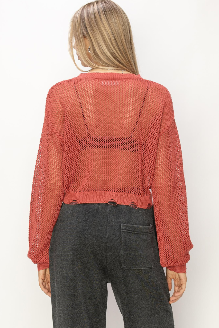 back view of junie distressed sweater in the color rust. model is wearing is with black sweatpants 