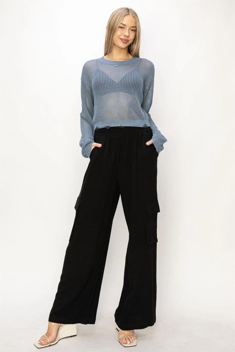 full  length front view of model wearing junie distressed knit sweater in the color ocean. model is wearing if with black cargo pants and wedge heel 