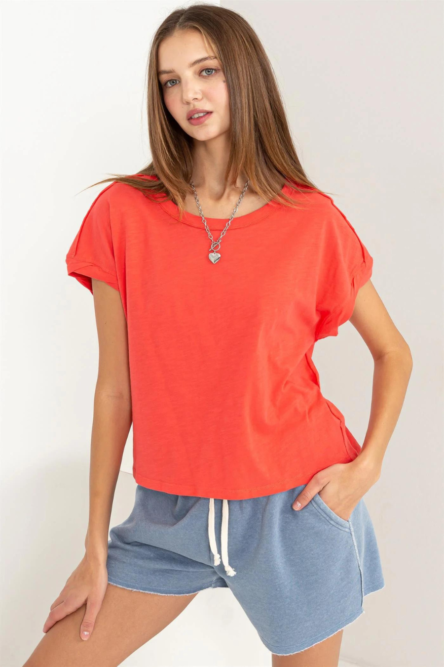close of front view of the hunter raw edge shirt in the color coral. model is wearing is with blue shorts 