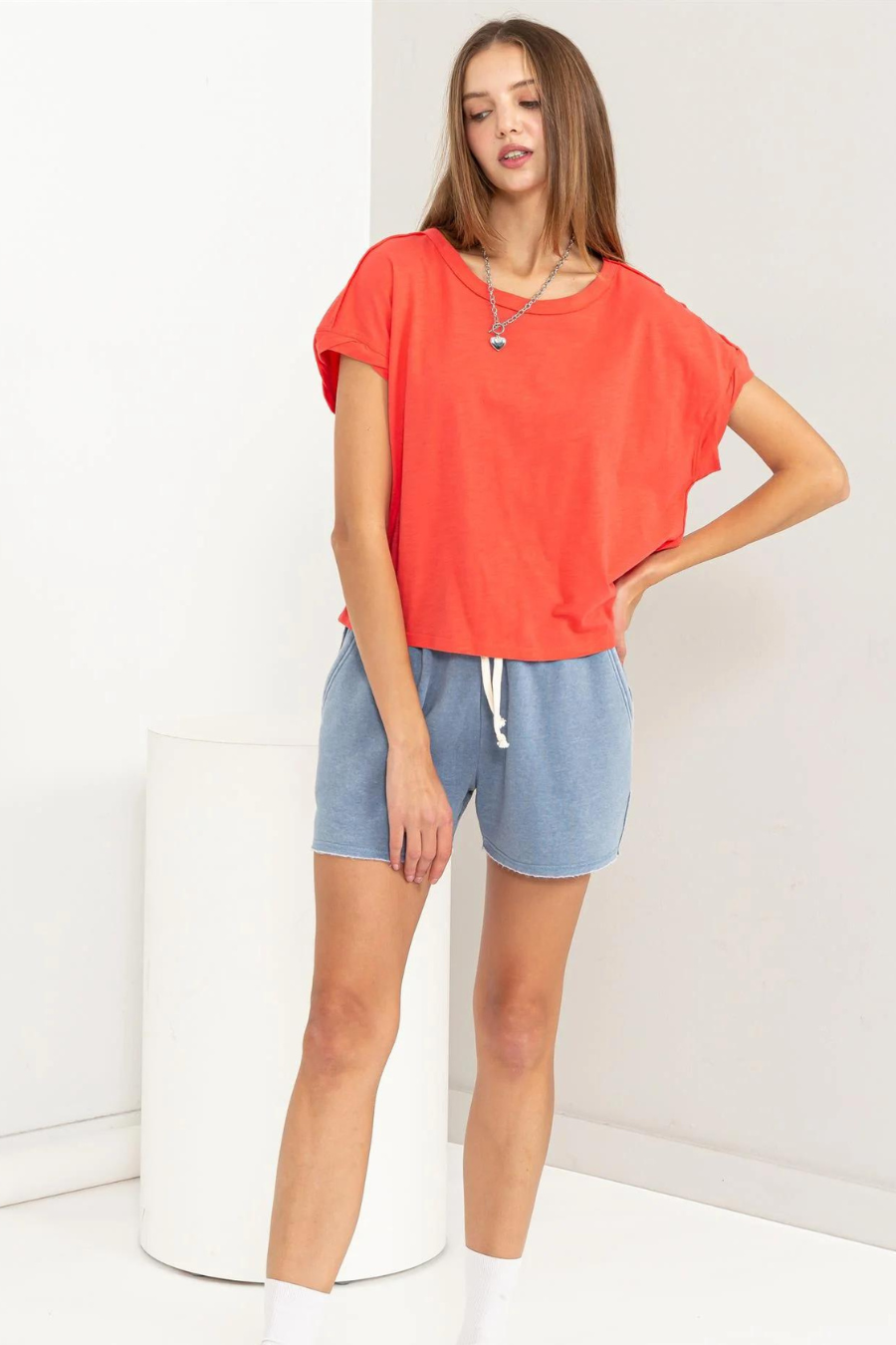 full front view of hunter raw edge shirt in the color coral. model is wearing it with blue shorts 