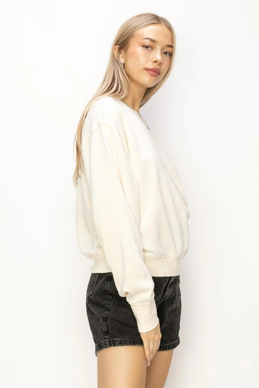 side front view of maxi pullover sweatshirt the color ivory, model is wearing is black denim  shorts 