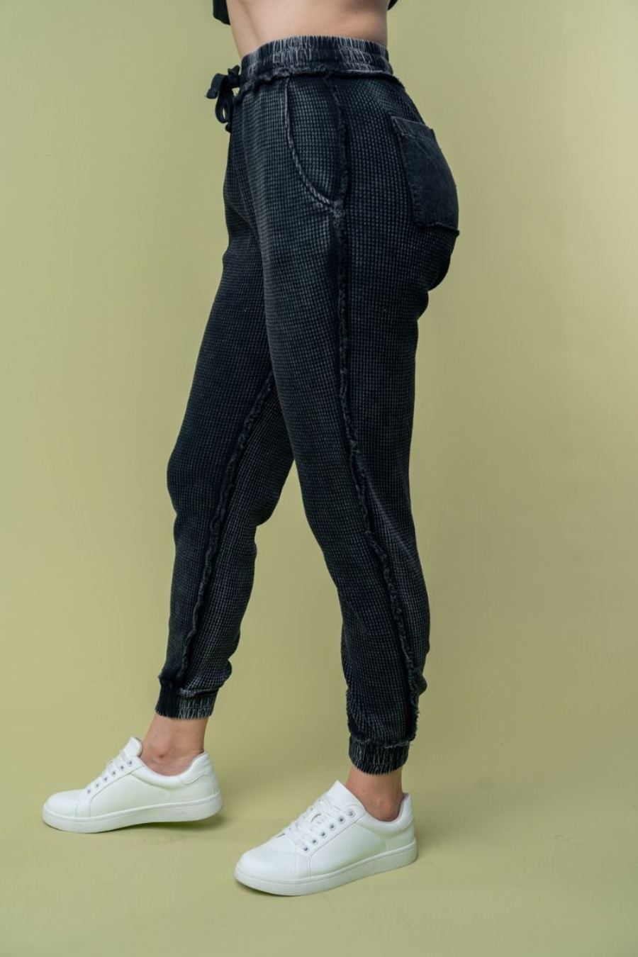 side view of hand high waisted thermal knit joggers in black. angle is showing off side and back pockets