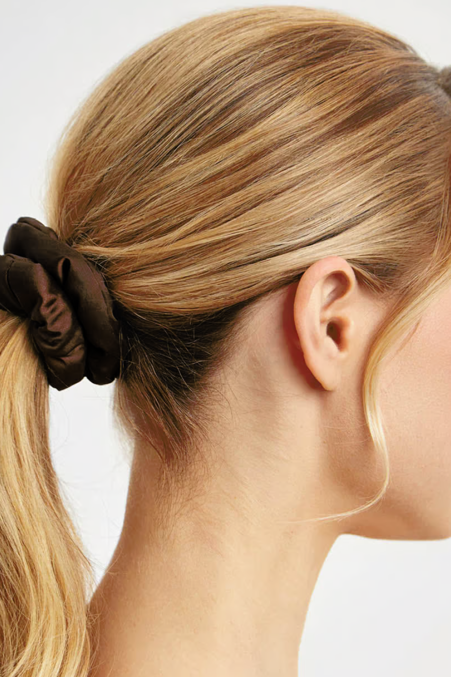 girl with blonde hair pulled into a ponytail with a brown satin Scrunchie