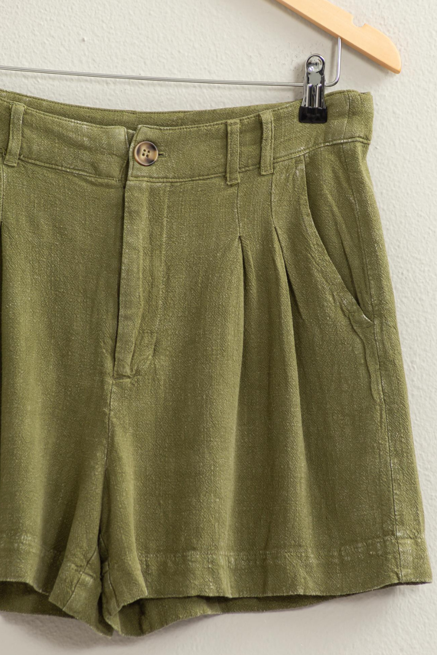 close up of olive shorts on wooden hanger