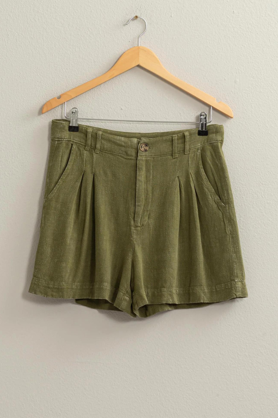 full length shot of olive linen shorts on a wooden hanger