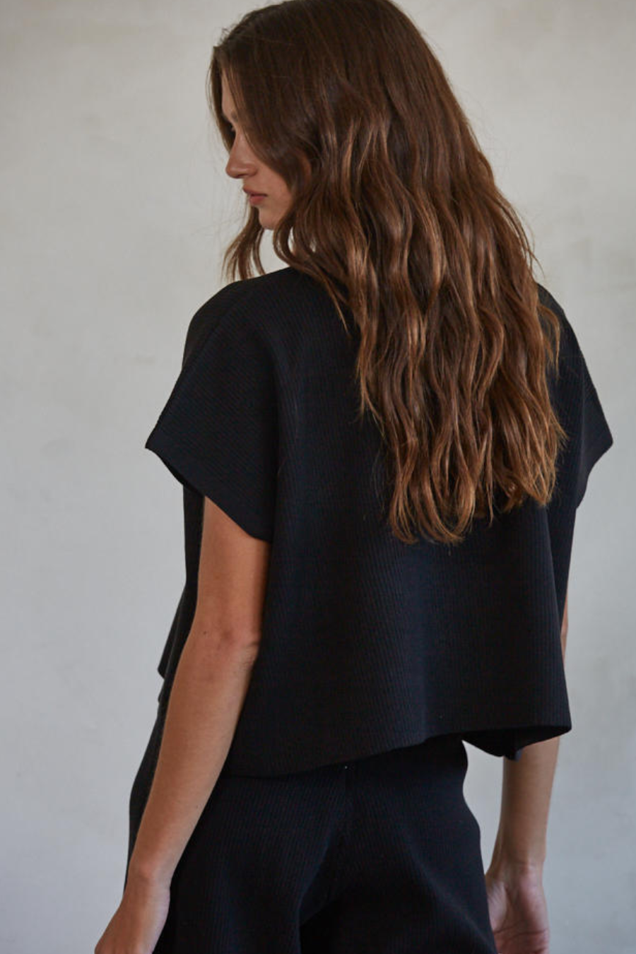 showing off the back of the black ribbed knit sweater top 