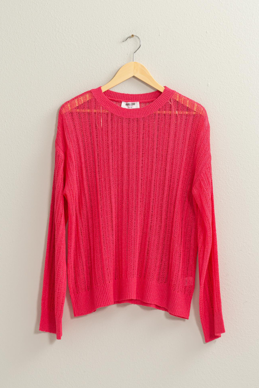front view of pink lottie sweater on a wooden hanger 