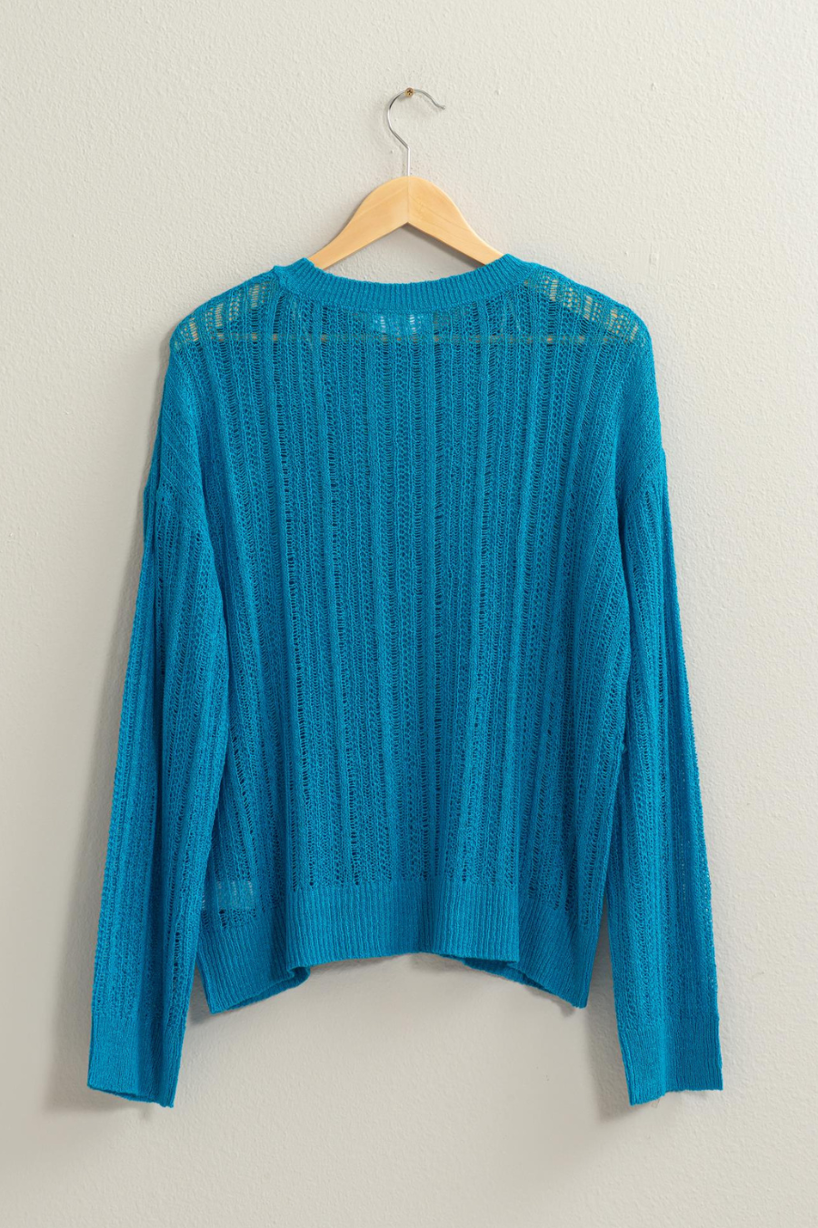 back view of blue Lottie sweater on a wooden hanger 