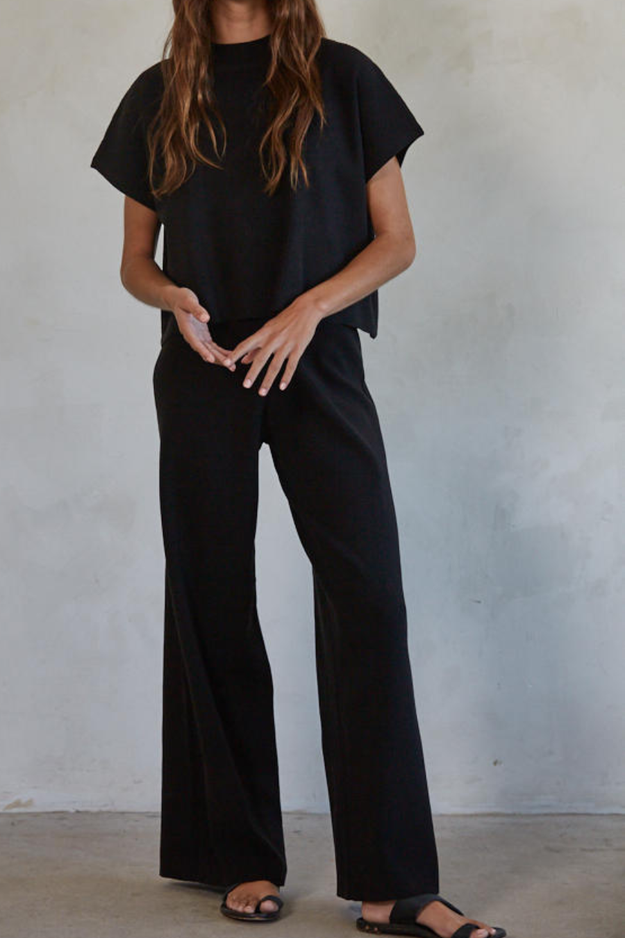 full shot of girl wearing black knit top and wide leg pants together 