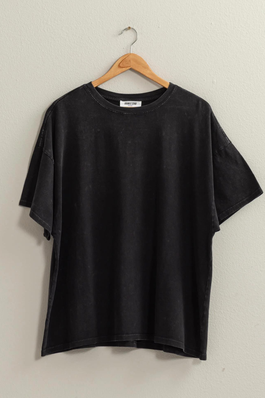 full view of Maisie over sized t in the color black, shirt is hanging on wooden hanger 