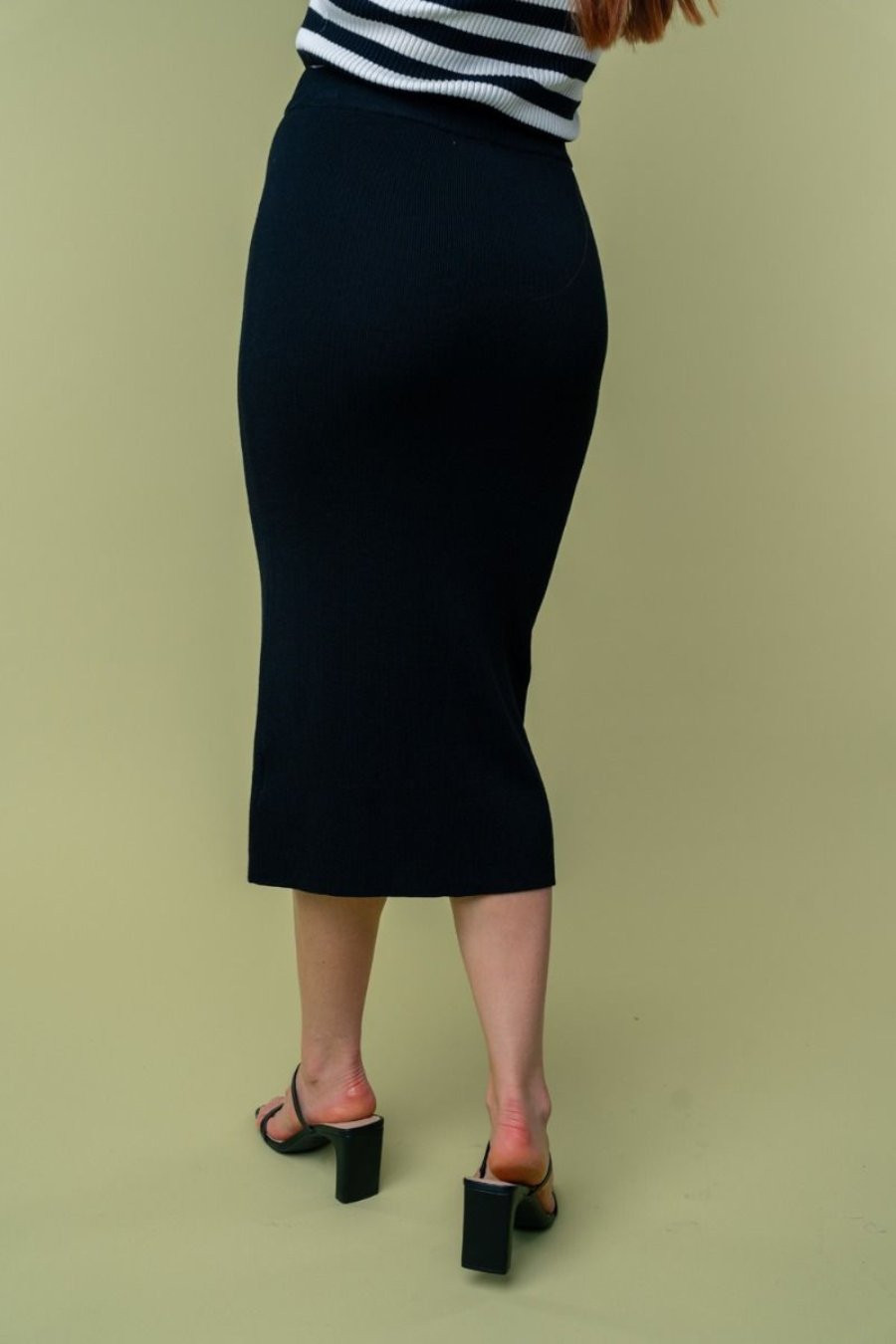 close up back view of Juliana high waisted knit midi skirt in the color black . model is wearing it with heels