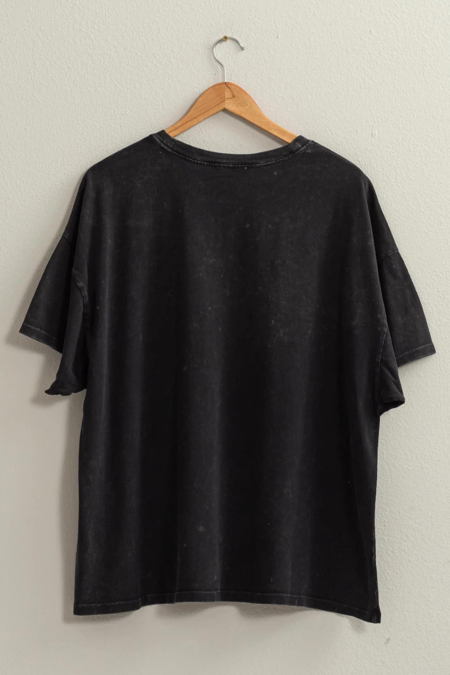 back view of Maisie over sized t shirt in the color black, shirt is hanging on a wooden hanger 