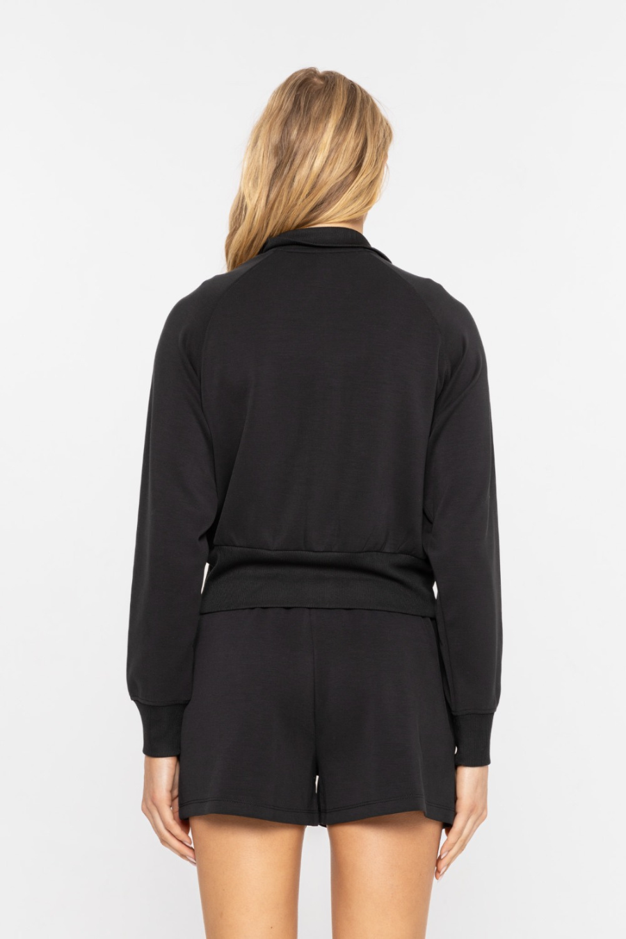 Close up back view of the cropped mock neck zip up jacket in the color black 