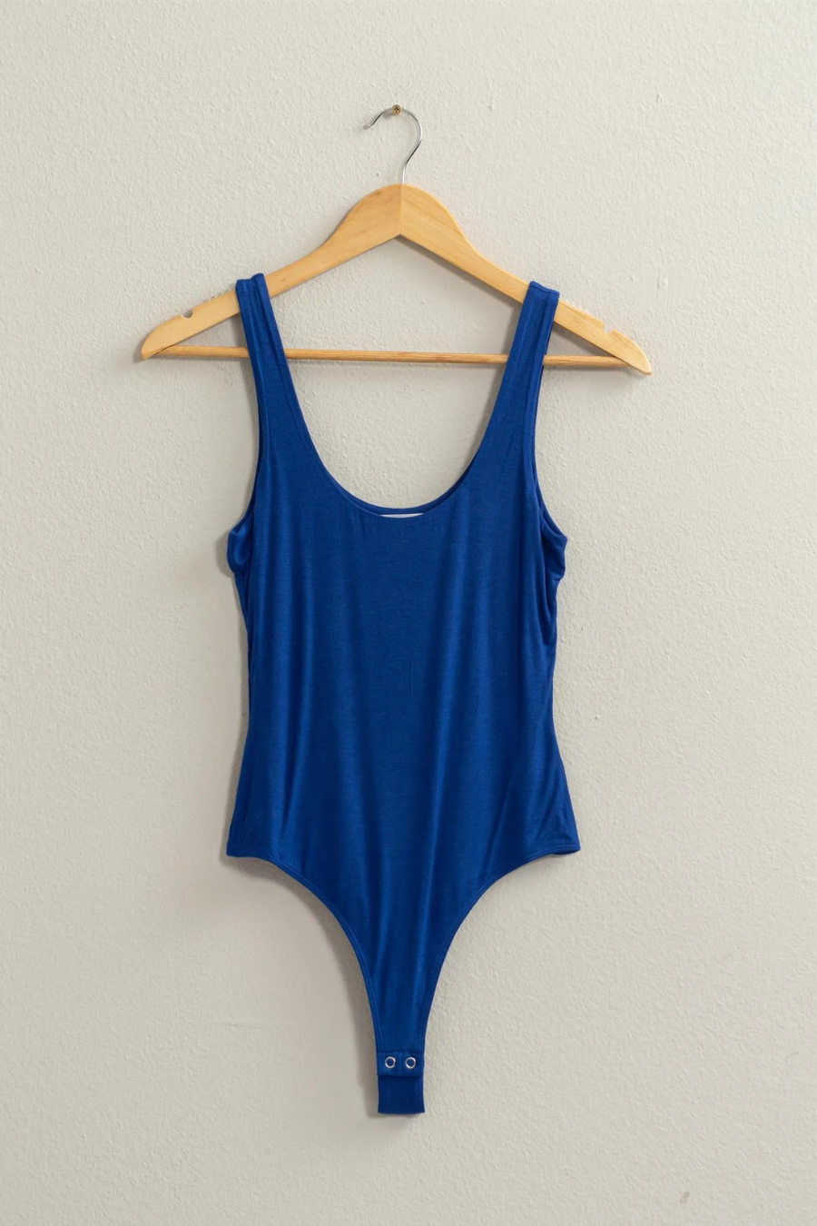 full front view of the Brinkley scoop bodysuit in the color blue, hanging on a wooden hanger
