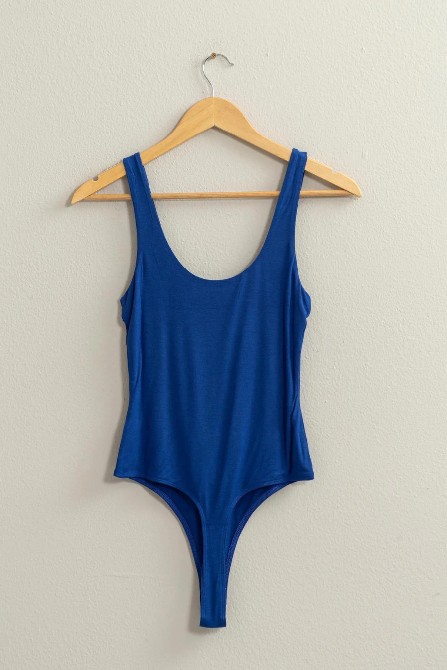 full length view of the Brinkley tank body suit, shown in the color blue, hanging on a hanger 