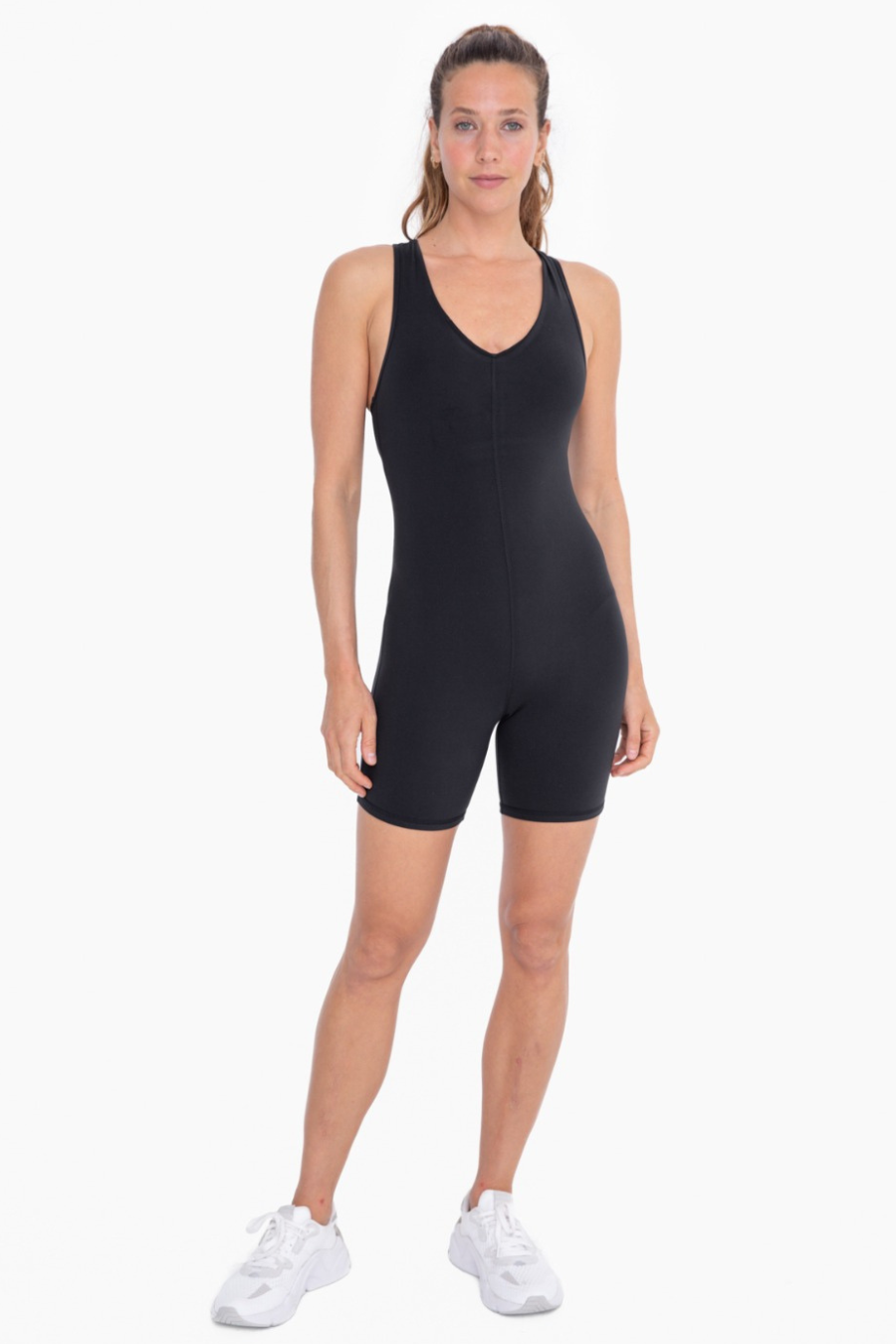 Full front view of the racerback v neck romper in black. model is wearing it with white tennis shoes.