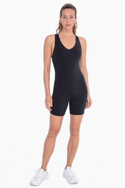 Full front view of the racerback v neck romper in black. model is wearing it with white tennis shoes.