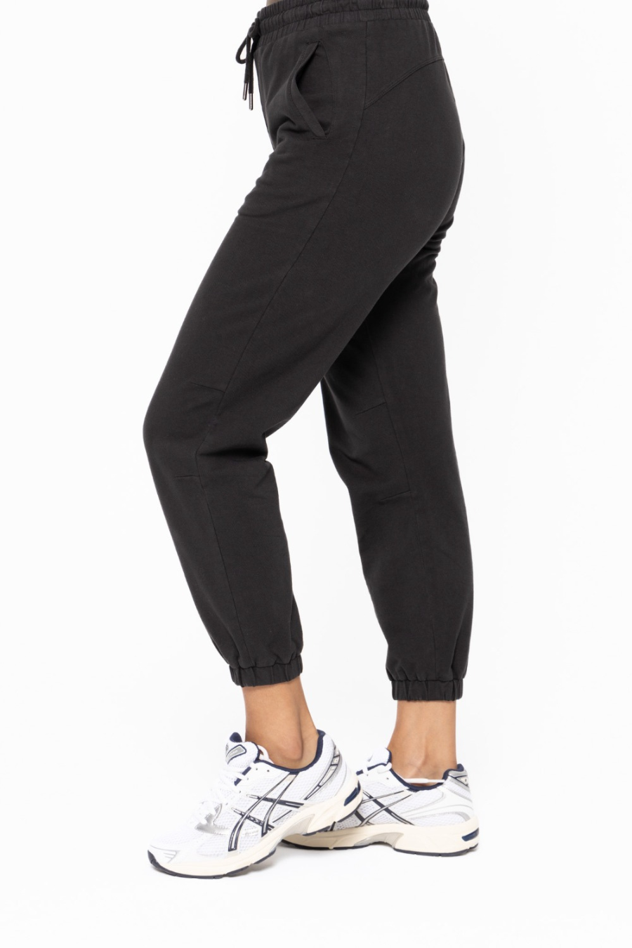 side close up view of the swoop back twill joggers in the color black. model is wearing them with white tennis shoes 