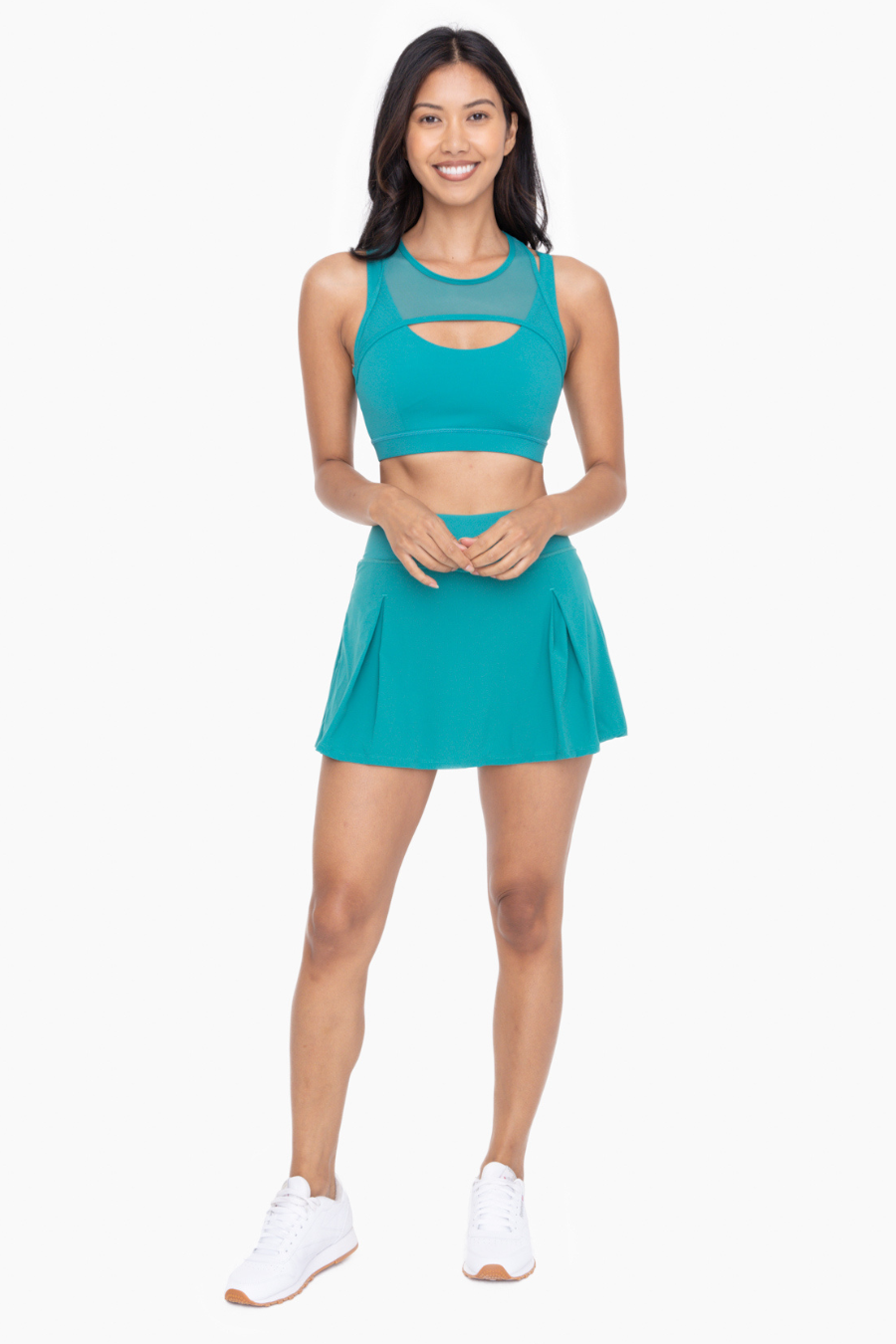 full length front view of the two pleat active tennis skort in the color teal, model is wearing it with corresponding spots bra top, sold separately 