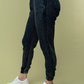 side view of hand high waisted thermal knit joggers in black. angle is showing off side and back pockets 