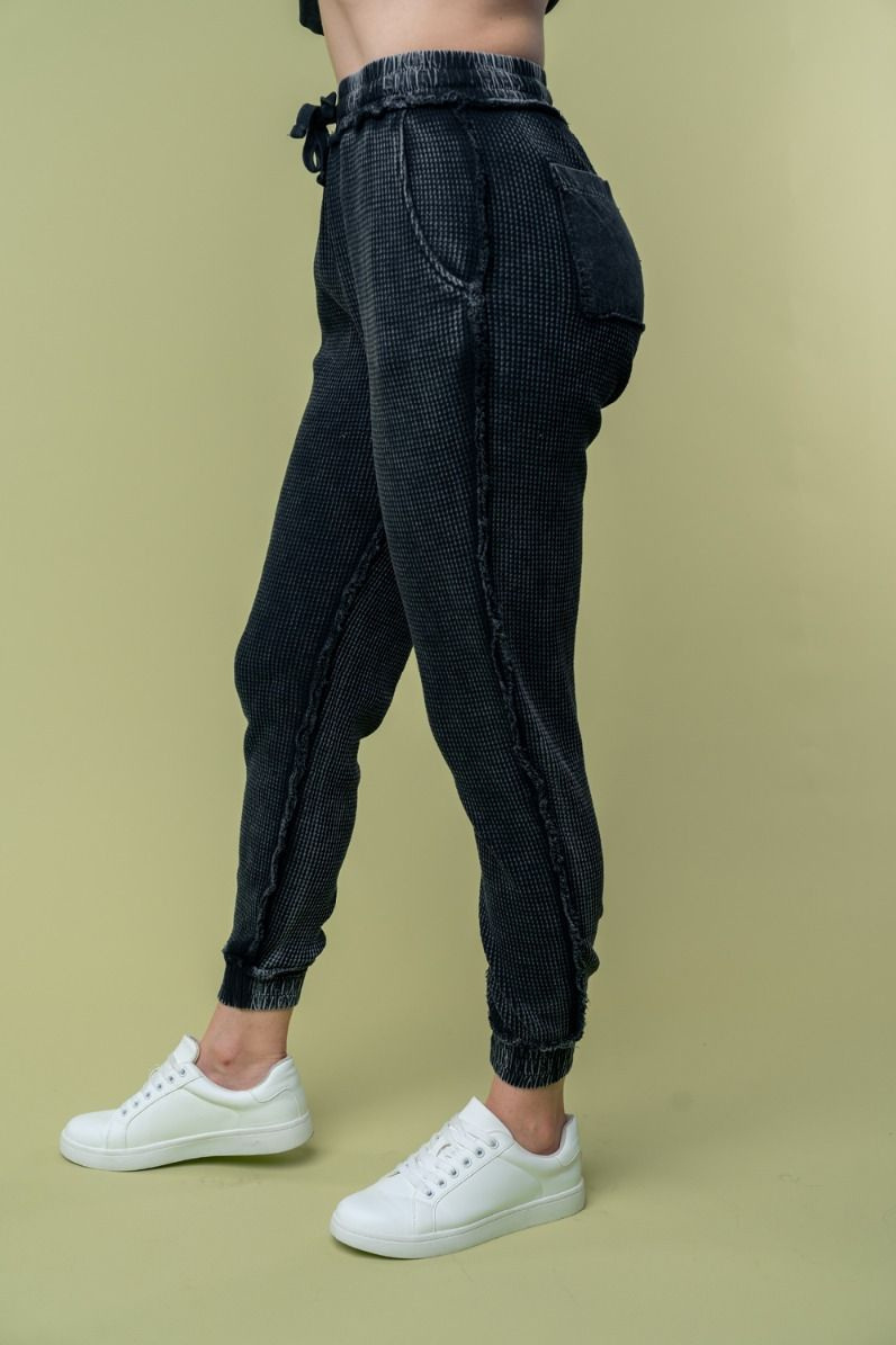 side view of hand high waisted thermal knit joggers in black. angle is showing off side and back pockets 