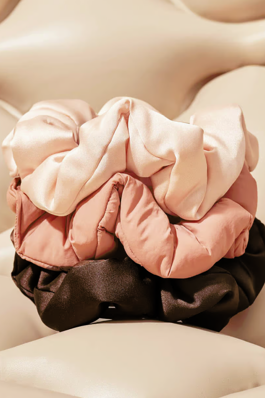 3 satin scrunchies stacked on top of each other, blush, rosewood, and brown