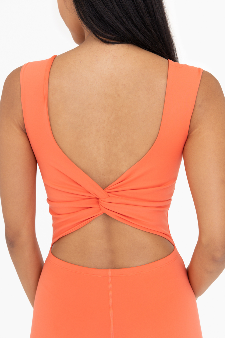 close up detail of the twist back on the venice jumpsuit in the color coral. twist back and cut detail. 