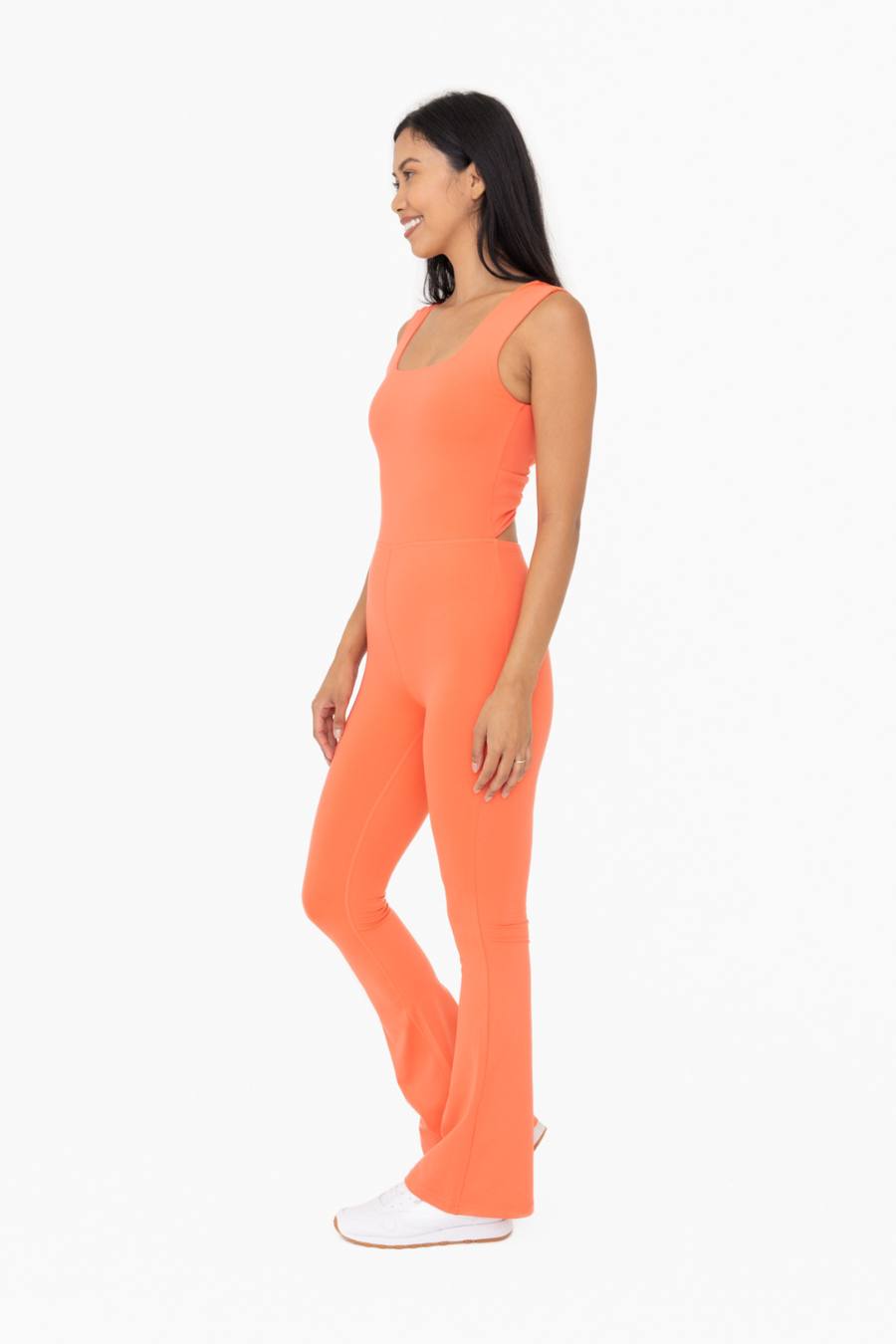 side view of the Venice twist back flare jumpsuit in the color coral 