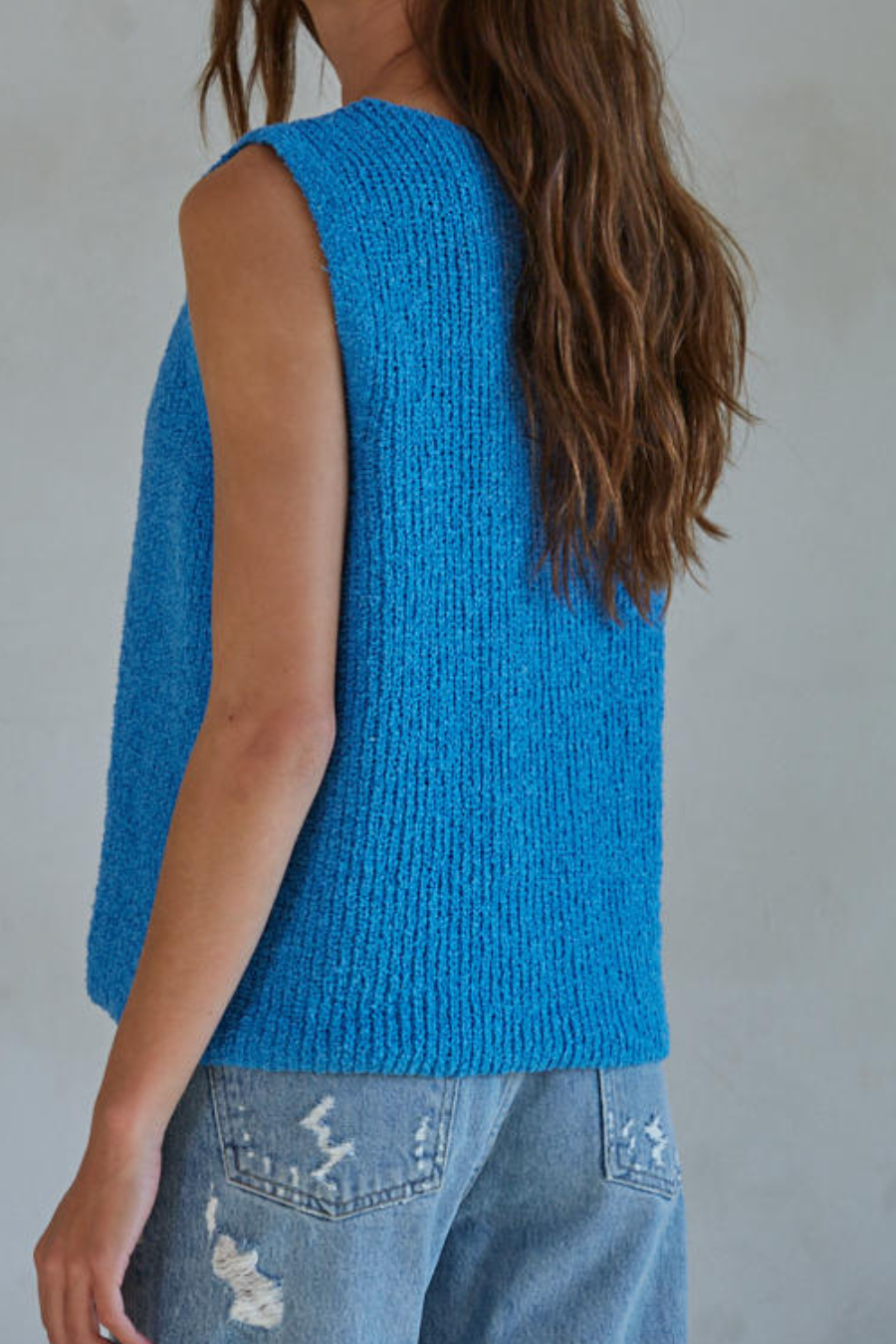 showing the back of the blue knit top paired with jeans 