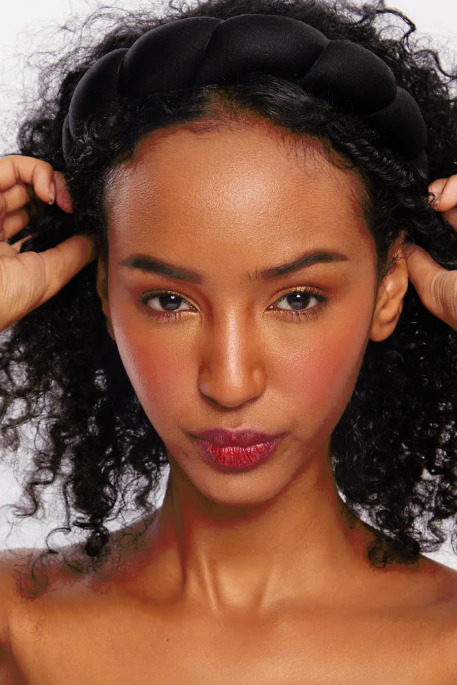 girl with curly hair putting black head band on 