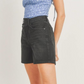 side view of girl wearing blue top with flowers on it and black denim shorts 