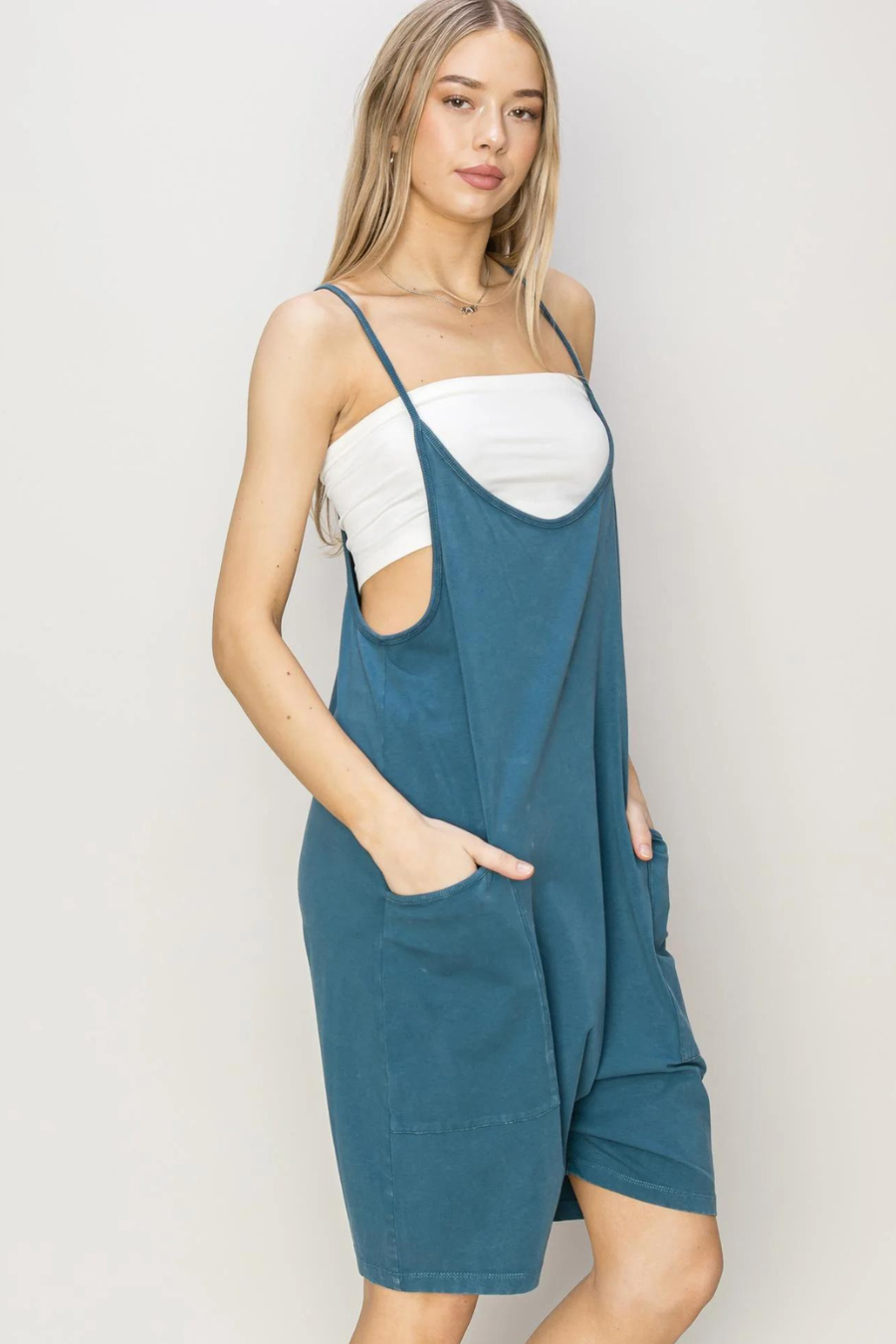 side view of girl wearing franny mineral romper in teal with a white cami under 