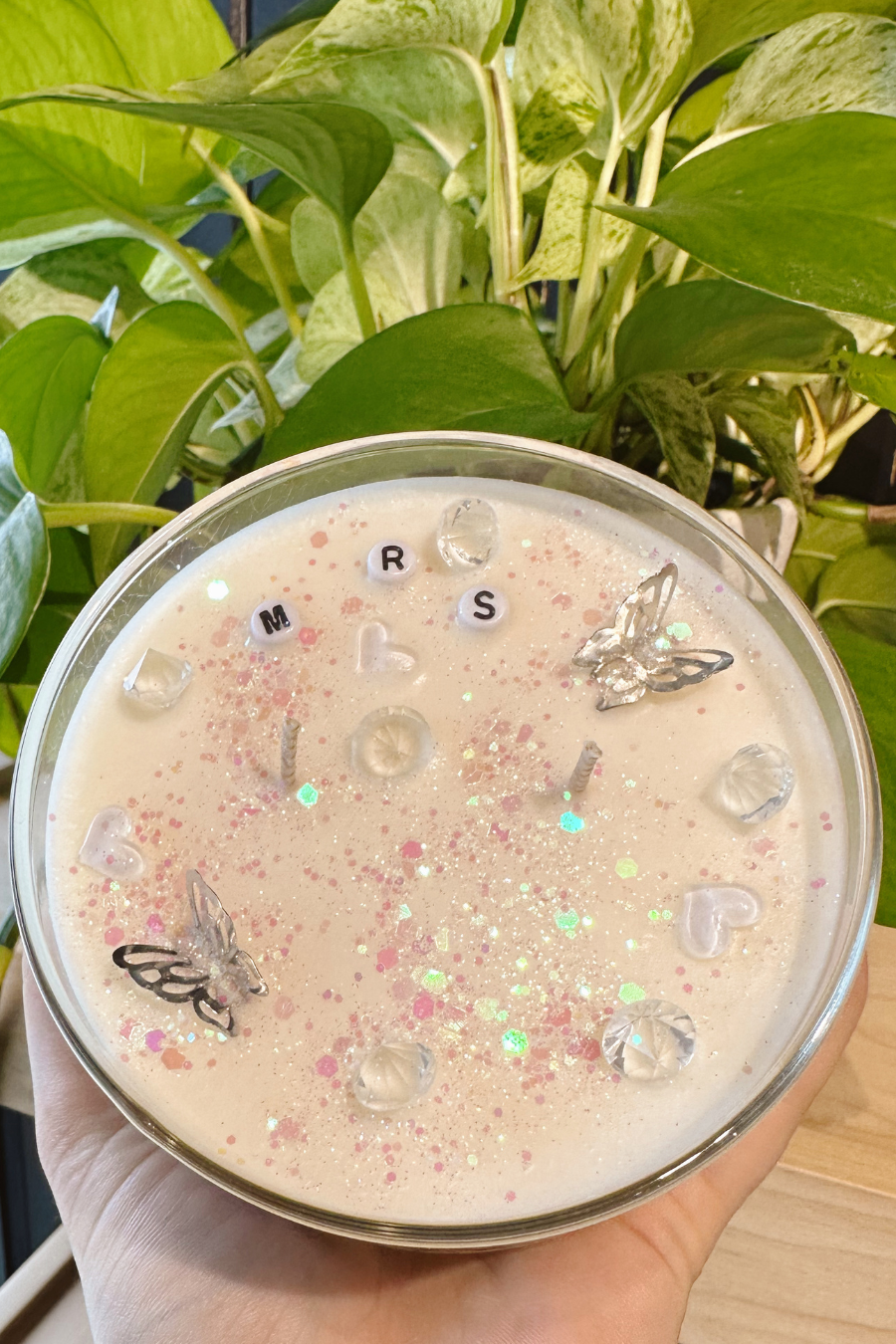inside of My Engaged Era Candle, sparkles, clear hearts, silver butterflies, and beads the say mrs