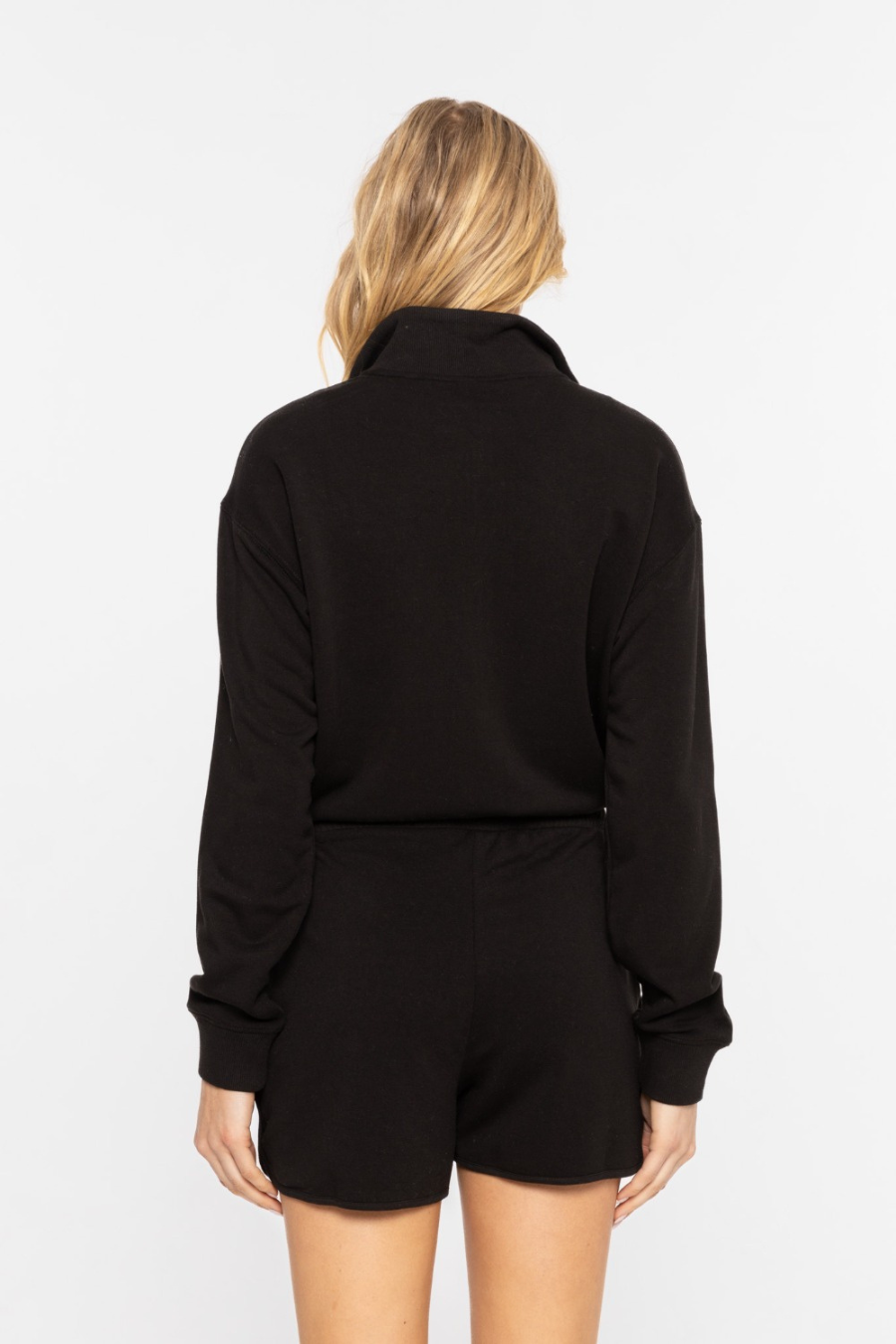 close up back view of long sleeve mock neck romper in black 