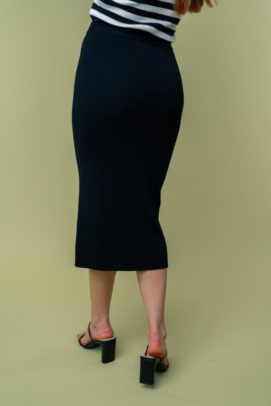 close up back view of Juliana high waisted knit midi skirt in the color black . model is wearing it with heels 