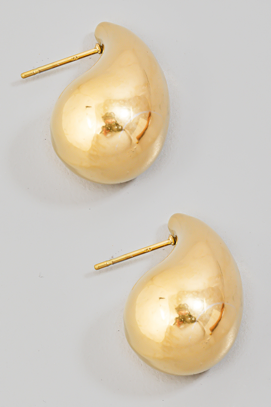gold teardrop earrings, as a flat lay